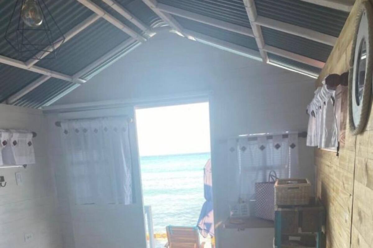 Una habitación con cama, paredes de madera y vista al mar, con una puerta que da al exterior.
