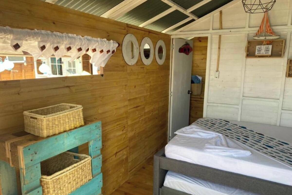 Una habitación acogedora con una cama, una pared de madera y una cesta sobre un banco azul.