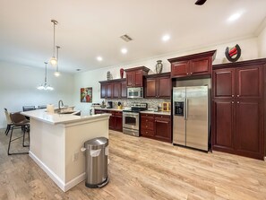 A modern kitchen with wooden cabinets, stainless steel appliances, and a central island.