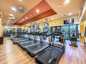 Ein Fitnessstudio mit mehreren Laufbändern, Trainingsgeräten und einem großen Fenster.