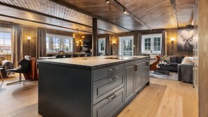 Una cocina amplia con una isla grande, techo de madera y ventanas amplias.