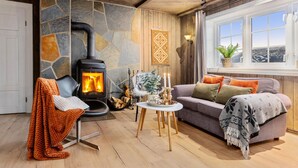 Una sala de estar acogedora con una pared de piedra, una chimenea, un sofá y un ventanal con vistas.