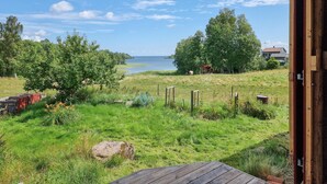 A grassy field with a wooden deck, a wooden fence, and a view of the sea. - Awesome home in Frändefors (Frändefors)