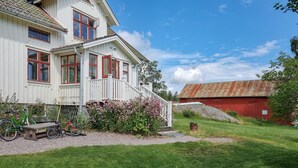 A white house with red trim, a porch, and a garden with flowers and a bench. - Awesome home in Frändefors (Frändefors)