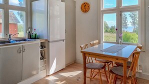 A kitchen with a white refrigerator, wooden chairs, a wooden table, and a clock on the wall. - Awesome home in Frändefors (Frändefors)