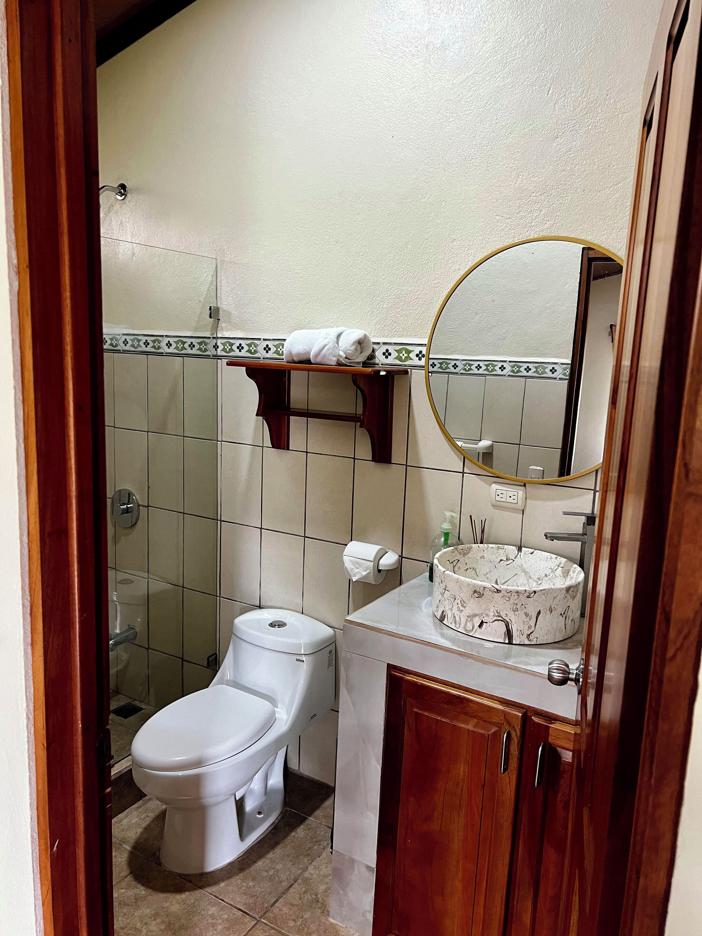 A compact bathroom with a toilet, sink, and mirror.