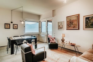 A modern living room with a dining area, a fireplace, and a view of mountains.