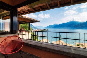 A balcony with a view of a lake and mountains, a red chair, and a railing. - Menaggio at its best - MyHomeinComo (Menaggio)