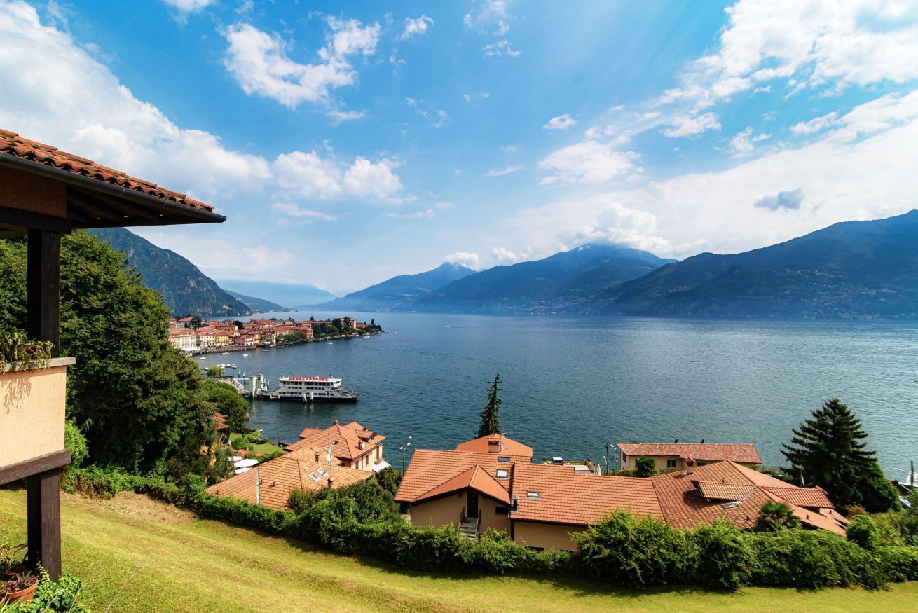 A lakeside view with buildings, a boat dock, and mountains in the background.