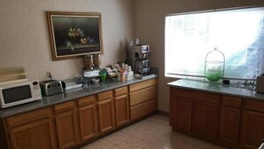 A kitchen with wooden cabinets, a microwave, a toaster, and a coffee maker. - Formosa Inn (Fresno)