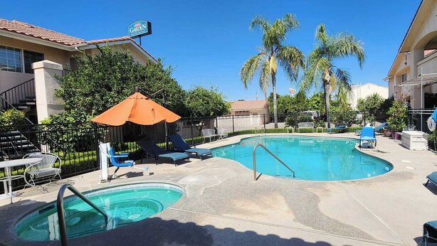 A pool area with two pools, lounge chairs, and umbrellas. - Formosa Inn (Fresno)