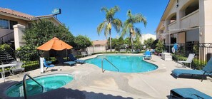 A pool area with two pools, lounge chairs, and umbrellas. - Formosa Inn (Fresno)