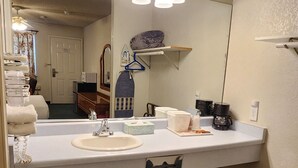 A bathroom with a large mirror, two sinks, a towel rack, and a hanging light fixture. - Formosa Inn (Fresno)