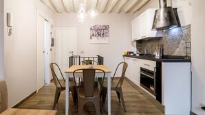 Eine kompakte Küche mit Essbereich, einer Decke mit freiliegenden Holzbalken und einer modernen Pendelleuchte.