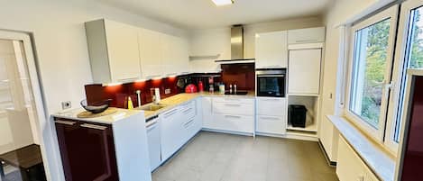 A modern kitchen with white cabinets, a built-in oven, and a window providing a view of the outdoors.