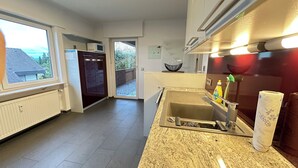 Een moderne keuken met een granieten aanrecht, een roestvrijstalen spoelbak en een raam met uitzicht op een balkon.