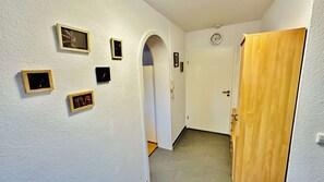 A hallway with white walls, a wooden door, and several framed pictures. - Daheim am Wasserturm – peace, style and a place to arrive and feel at home (Wörth am Rhein)