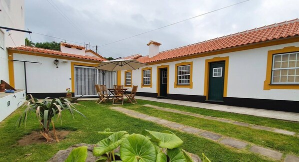 Guests can enjoy a tranquil courtyard with a patio area, surrounded by lush greenery and a low wall.