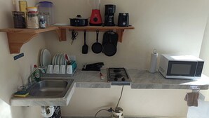 A compact kitchen with a sink, stove, microwave, and various utensils. - Cómodo, céntrico a cuadra y media de playa norte (Isla Mujeres)