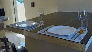 A dining area with a table set for two, a TV mounted on the wall, and a door leading outside. - Cómodo, céntrico a cuadra y media de playa norte (Isla Mujeres)