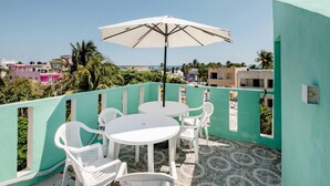 A rooftop terrace with a table and chairs, an umbrella, and a view of the cityscape. - Cómodo, céntrico a cuadra y media de playa norte (Isla Mujeres)