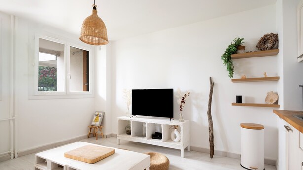 A modern living room with a television, white furniture, and decorative shelves. - Appartement Lavoisier - Welkeys (Puteaux)