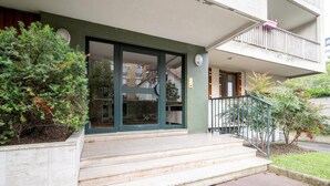 A building entrance with a green door, a small balcony, and steps leading up to the door. - Appartement Lavoisier - Welkeys (Puteaux)