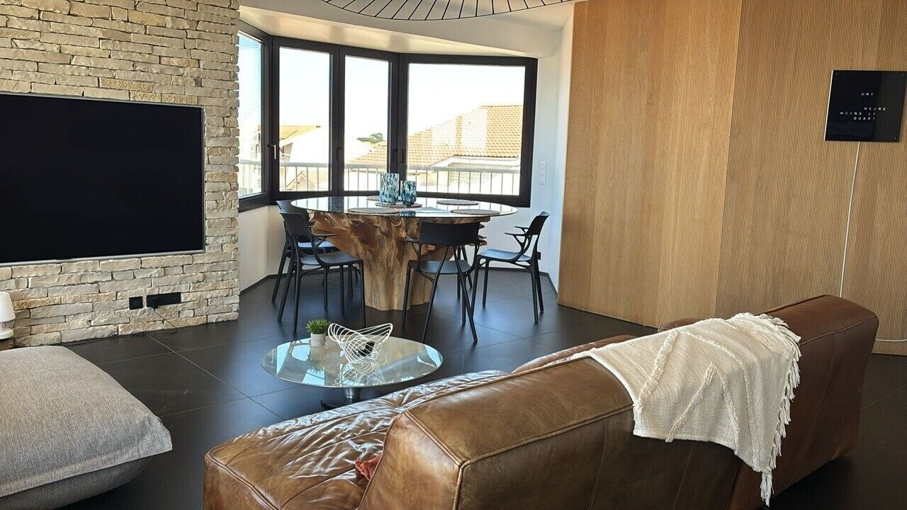 Un salon moderne avec un mur en pierre, un téléviseur à écran plat, une table de salle à manger ronde avec des chaises, une table basse en verre et un canapé en cuir.
