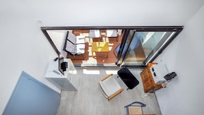 A high ceiling room with a skylight, a small table with a vase, a chair, and a cabinet with a microwave. - Amazing apartment in Le Barcarès (Le Barcarès)