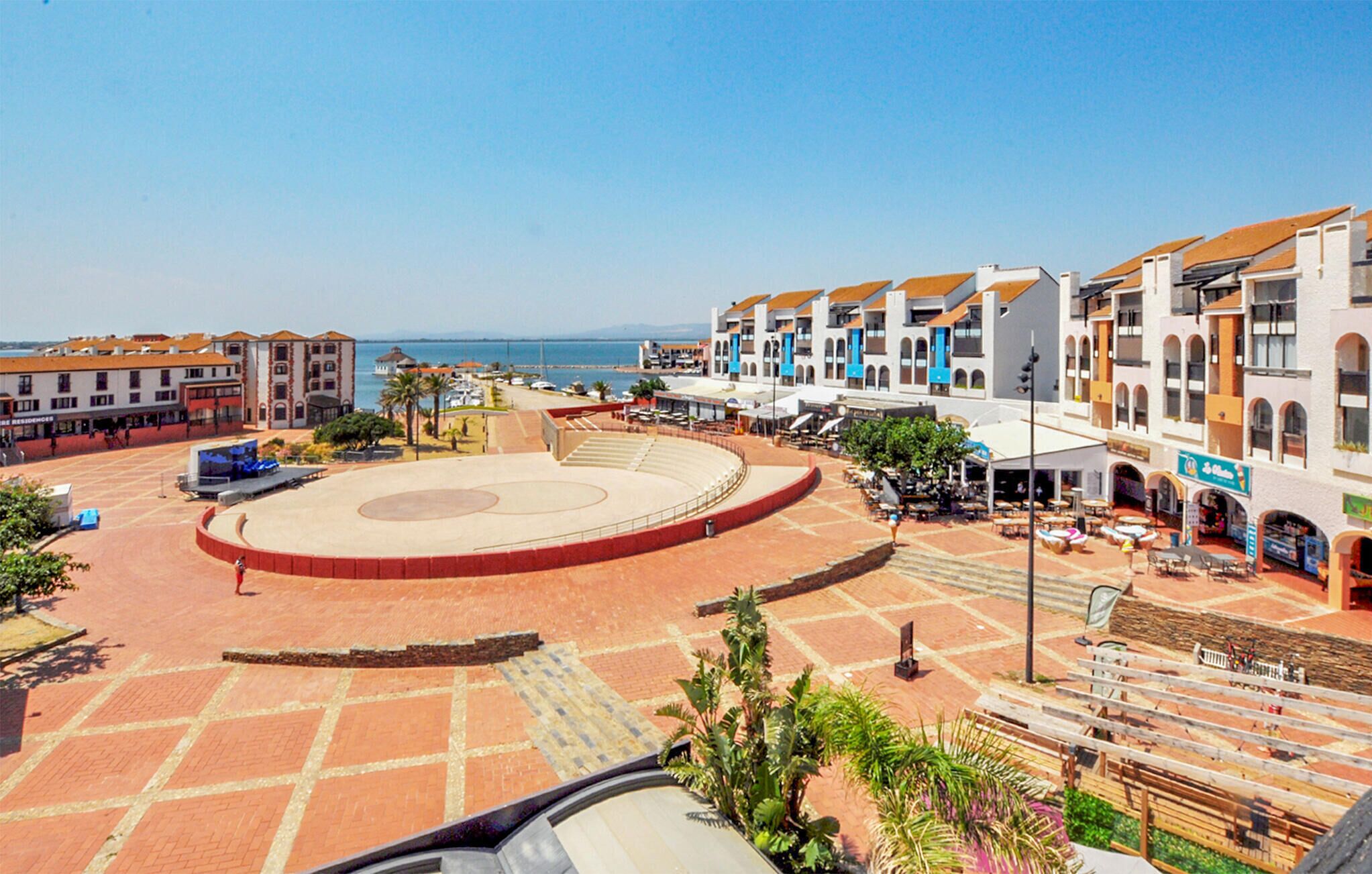 A plaza with a central open space, surrounded by multi-story buildings with commercial establishments on the ground floor.