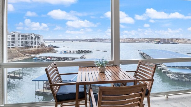 A wooden table and chairs with a view of a river and buildings across the water.