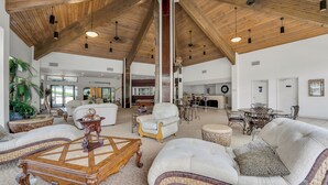 A spacious living area with high ceilings, wooden beams, and a variety of seating options including sofas and armchairs.