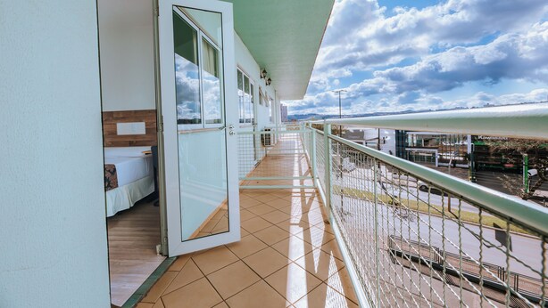 Uma varanda com vista para a rua, uma porta para um quarto e um chão de azulejos.