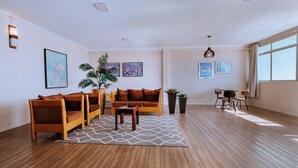 Uma sala de estar moderna com piso de madeira, um conjunto de sofá, uma mesa de centro e um espaço de jantar com cadeiras.