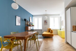 Un ambiente moderno con un tavolo da pranzo in legno, sedie gialle, un divano e un pavimento con un motivo a spina di pesce.