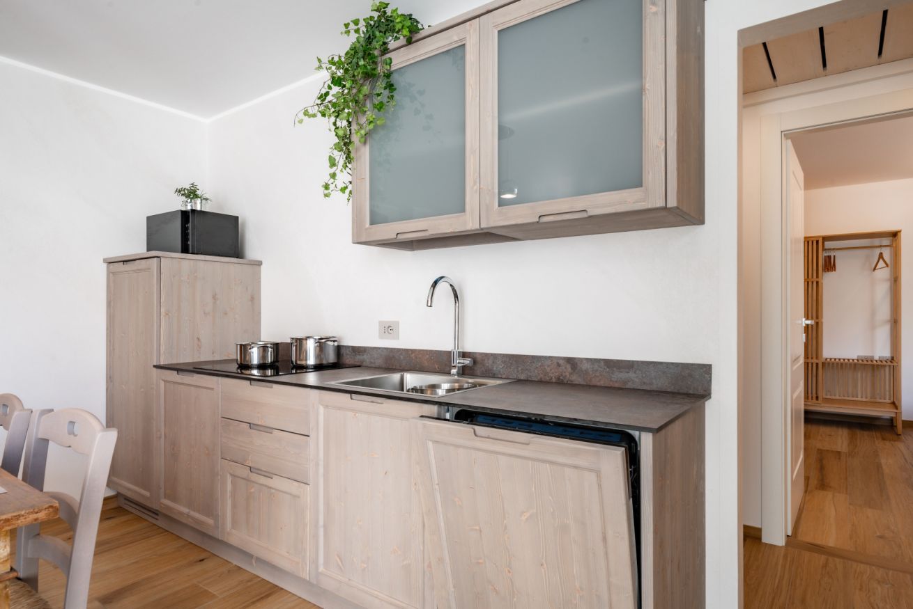 Une cuisine moderne avec des meubles de couleur bois clair, un évier en acier inoxydable et un lave-vaisselle encastré.