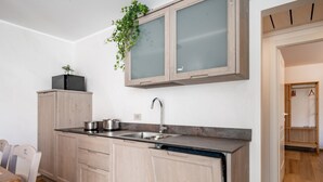A modern kitchen with light wood cabinets, a stainless steel sink, and a built-in dishwasher. - Villa Sunset - with pool and large garden - few steps from the beach (Dervio)