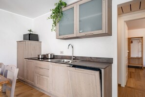 A modern kitchen with light wood cabinets, a stainless steel sink, and a built-in dishwasher. - Villa Sunset - with pool and large garden - few steps from the beach (Dervio)