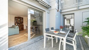 Una cocina moderna con comedor, una puerta corrediza de vidrio que da a una sala de estar y un pequeño espacio exterior con asientos.