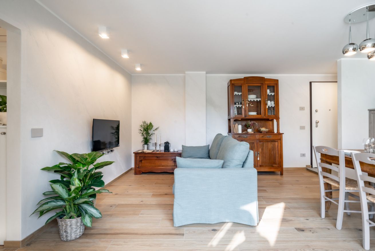 Un salon moderne avec un canapé, un meuble en bois et un coin repas avec des chaises.