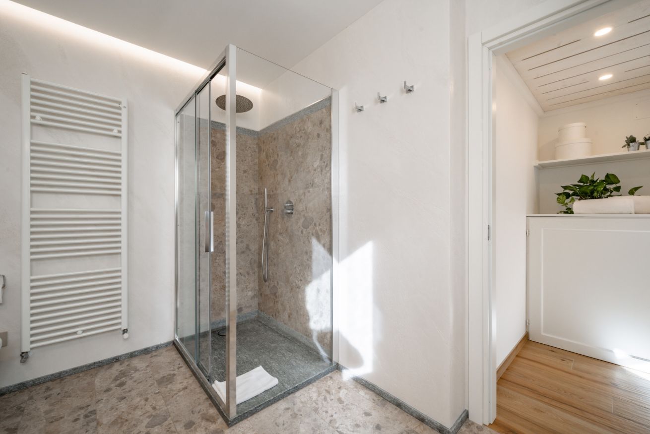Une salle de bain moderne avec une douche à parois de verre, un radiateur blanc et un plancher en bois.