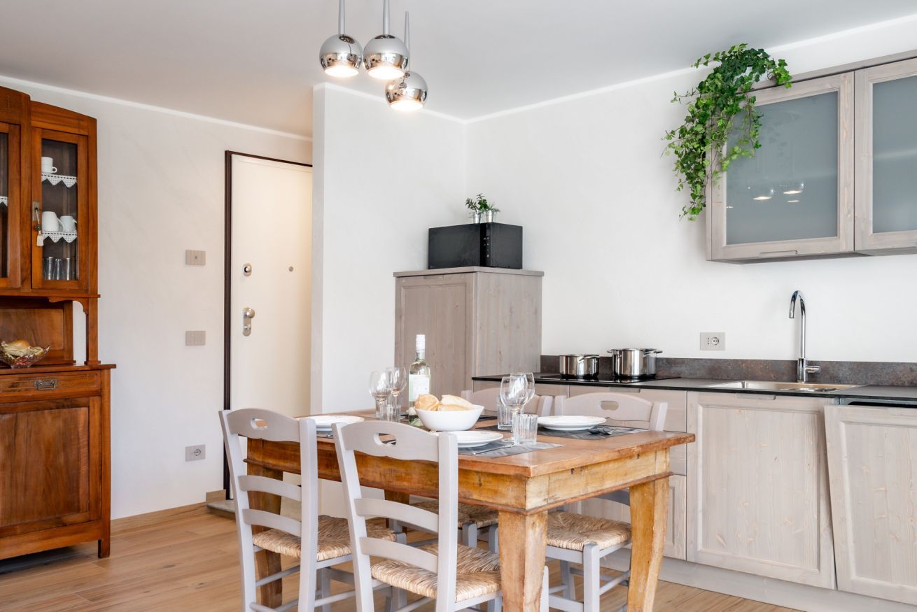 Une cuisine moderne avec une table à manger en bois, des chaises blanches et un four encastré.