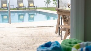 A view of a swimming pool with lounge chairs and a covered area in the background.