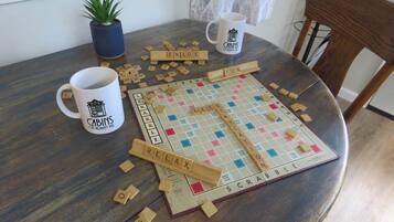 Un juego de Scrabble sobre una mesa redonda de madera, con una taza de café y una planta en maceta.