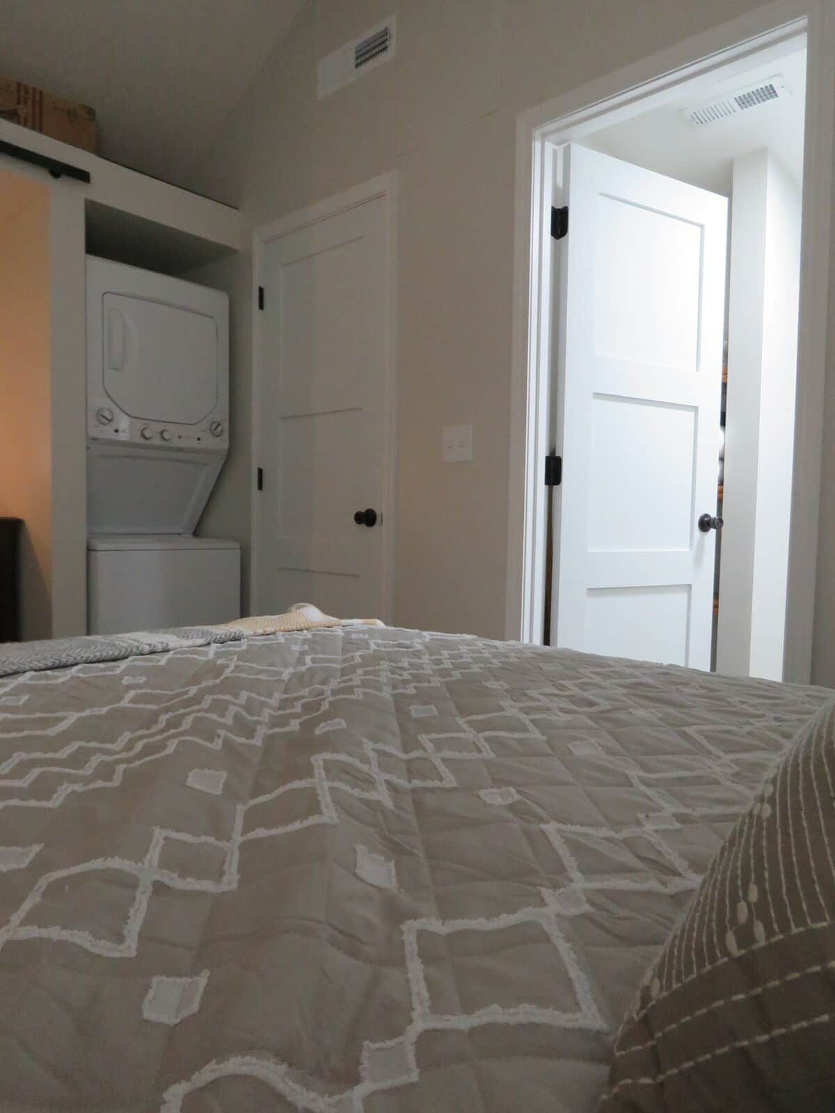 A bedroom with a bed, a wardrobe, and a door leading to another room.