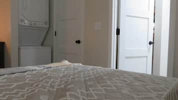 A bedroom with a bed, a wardrobe, and a door leading to another room.