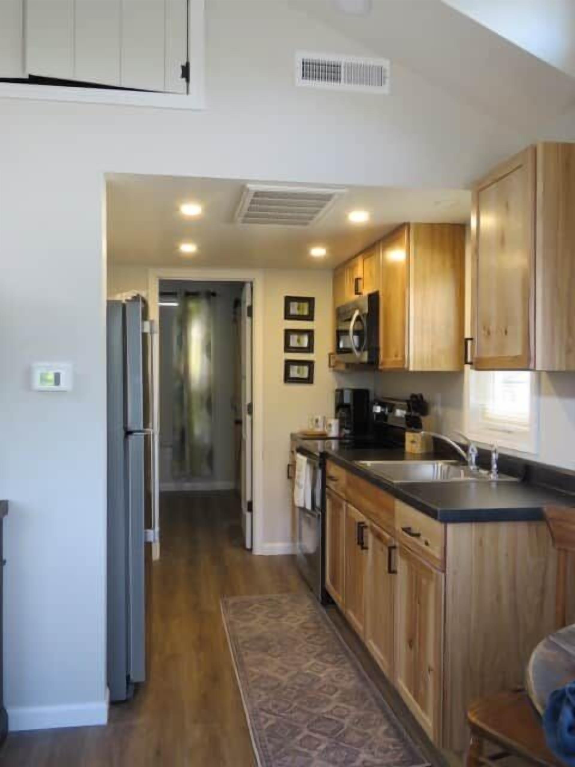 A kitchen with wooden cabinets, a refrigerator, a microwave, and a sink.