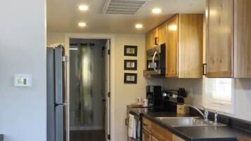 A kitchen with wooden cabinets, a refrigerator, a microwave, and a sink.