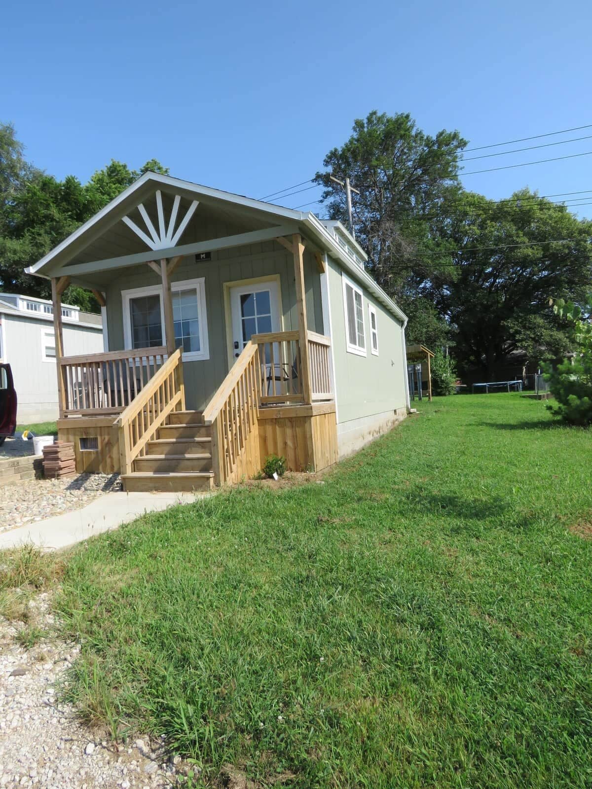 A small, single-story house with a front porch and a staircase leading to the entrance.
