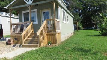 A small, single-story house with a front porch and a staircase leading to the entrance.